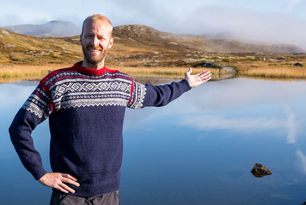 Man in Norway with Norwegian knitted sweater standing in front of a lake